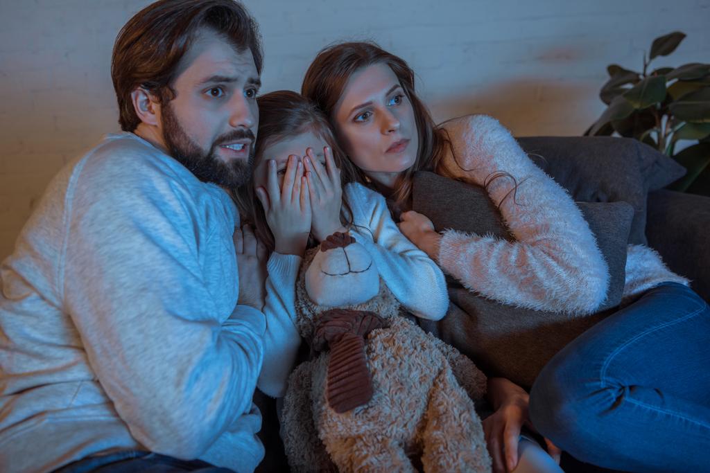ouders en dochter horrorfilm kijken in de avond thuis - Foto, afbeelding