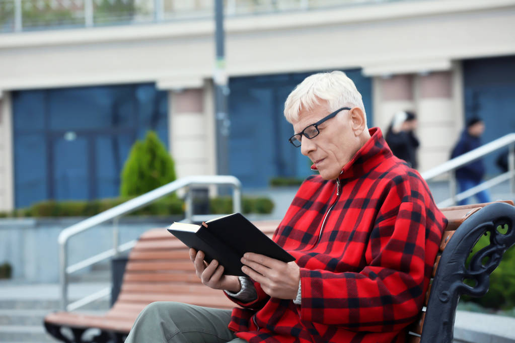bello maturo uomo lettura libro su panchina all'aperto
 - Foto, immagini