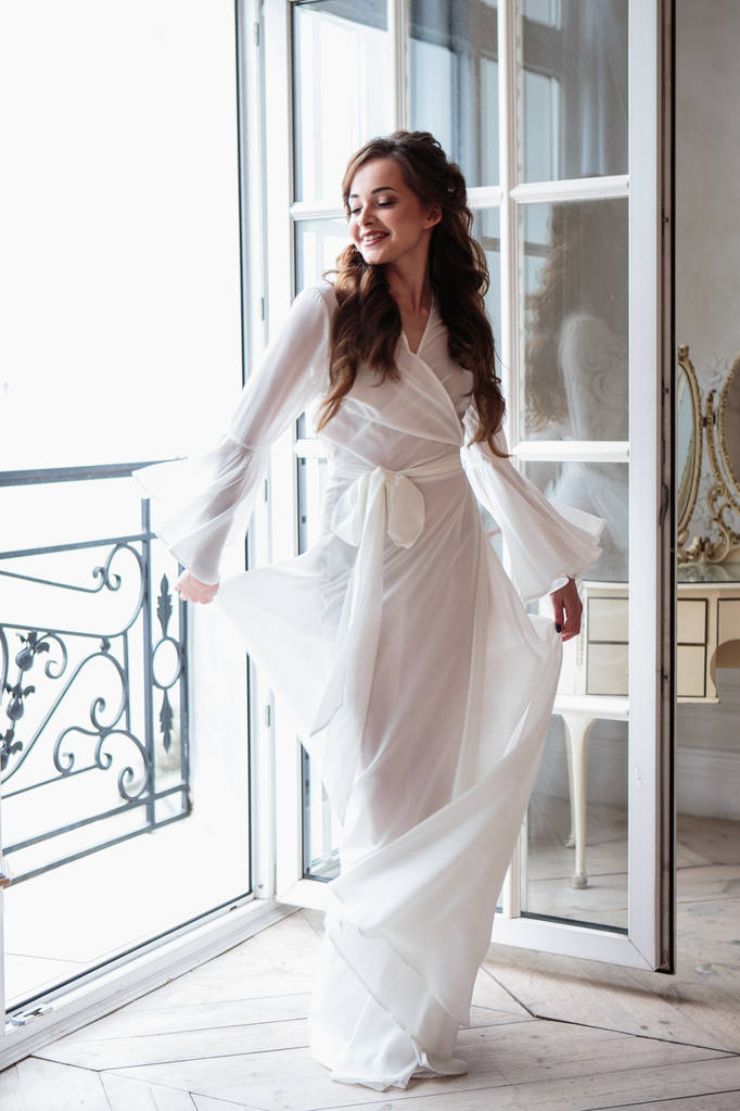 Krásná nevěsta v bílé svatební peignoir v ráno. krásy portrét v interiéru - Fotografie, Obrázek
