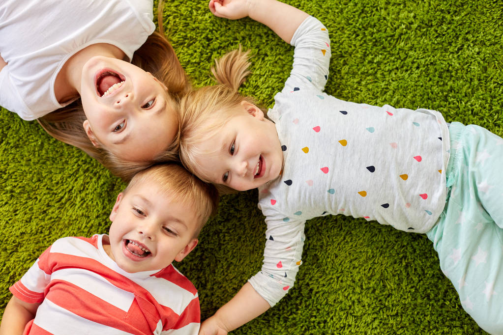 bambini felici sdraiati sul pavimento o sul tappeto
 - Foto, immagini