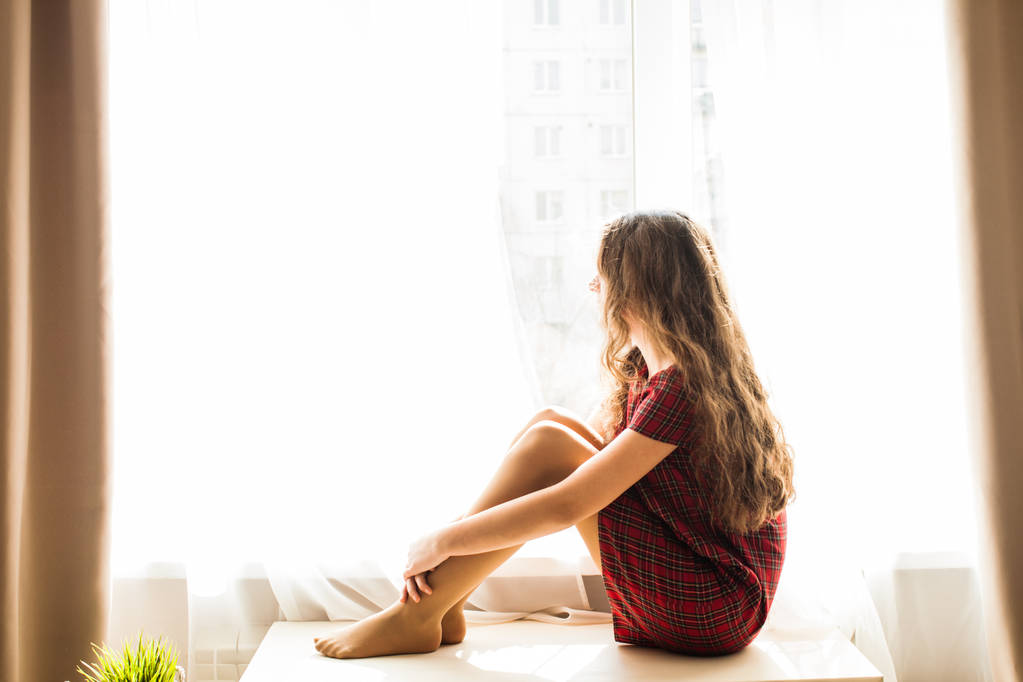 Ładny nastolatek dziewczyna siedzi w pobliżu okna - Zdjęcie, obraz
