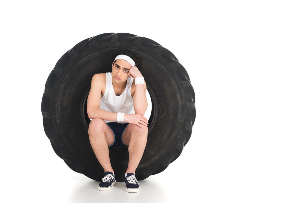 Jonge dunne sportman zit in wiel geïsoleerd op wit - Foto, afbeelding