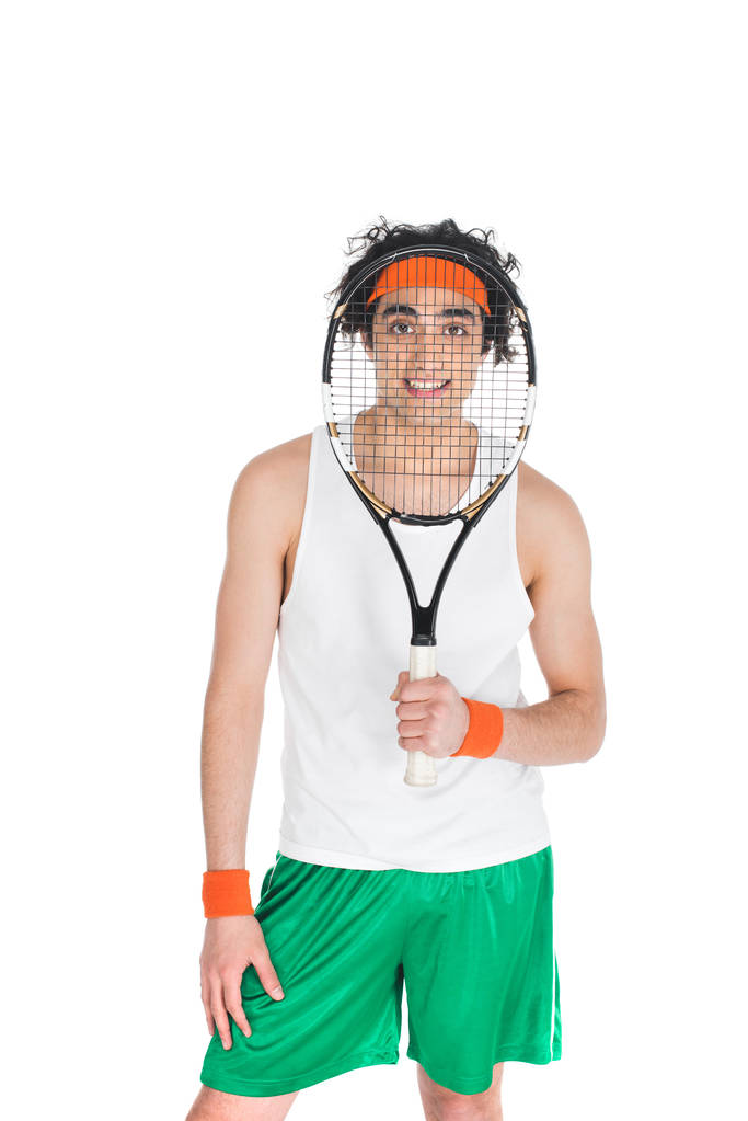 Jeune sportif maigre regardant à travers la raquette de tennis isolé sur blanc
 - Photo, image