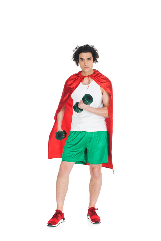 Thin sportsman with dumbbells in hands standing in red cape isolated on white - Photo, Image