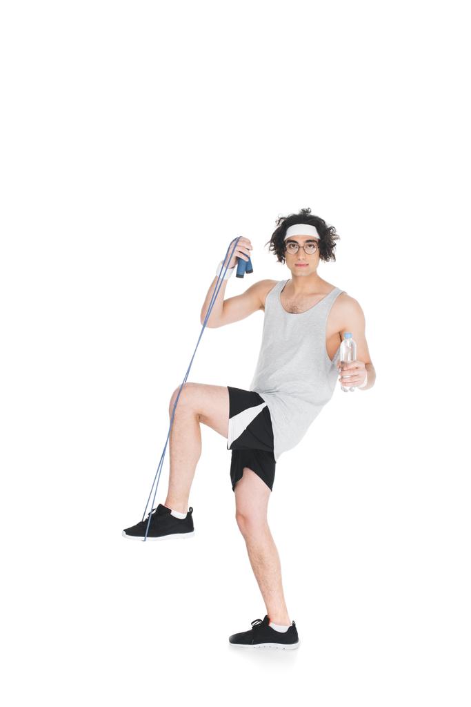Молодой тощий спортсмен в очках с скакалкой и бутылкой воды, изолированной на белом
 - Фото, изображение