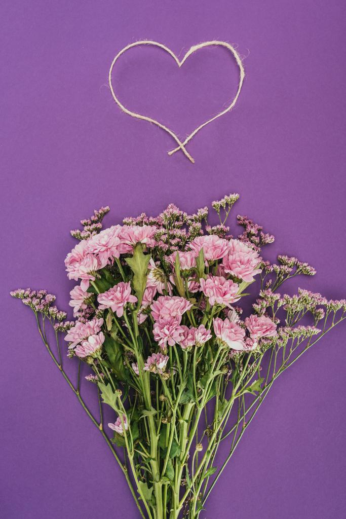bouquet de belles fleurs roses et corde en forme de coeur sur violet
 - Photo, image