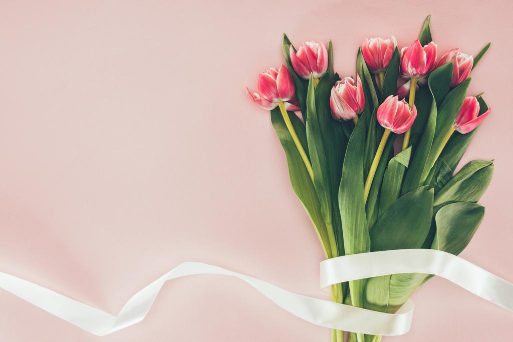 bouquet de belles tulipes roses aux feuilles vertes et ruban sur rose
  - Photo, image
