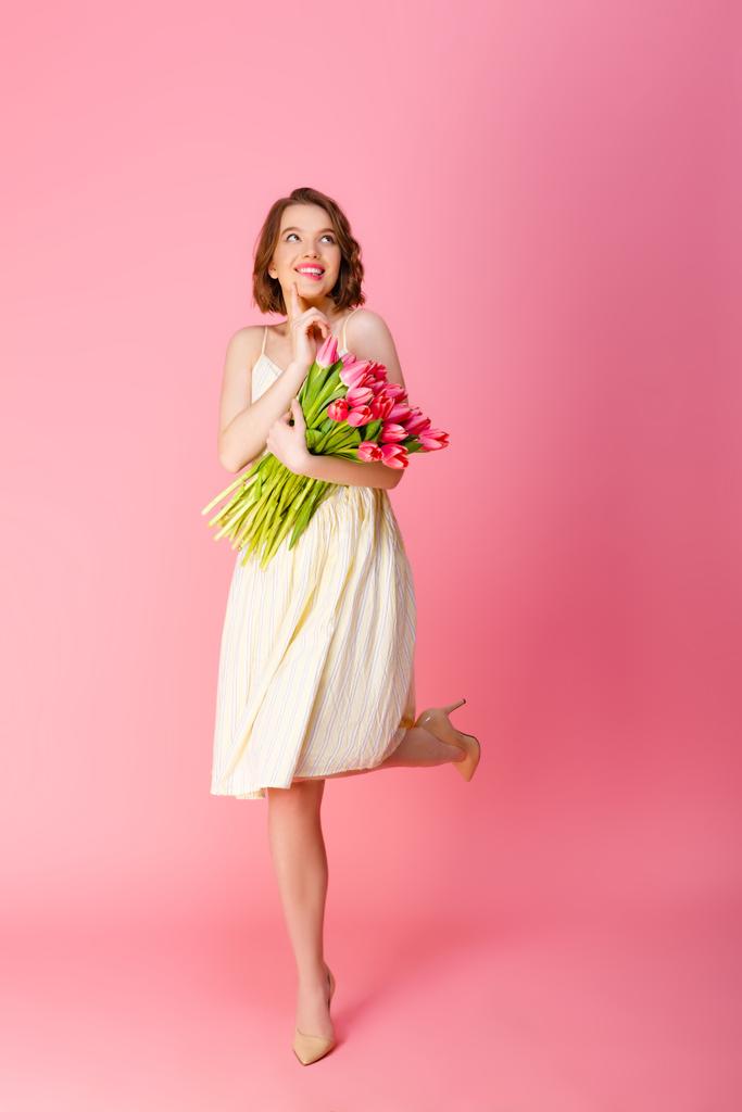 ピンクに分離されたピンクのチューリップの花束を持つ夢のような女性 - 写真・画像
