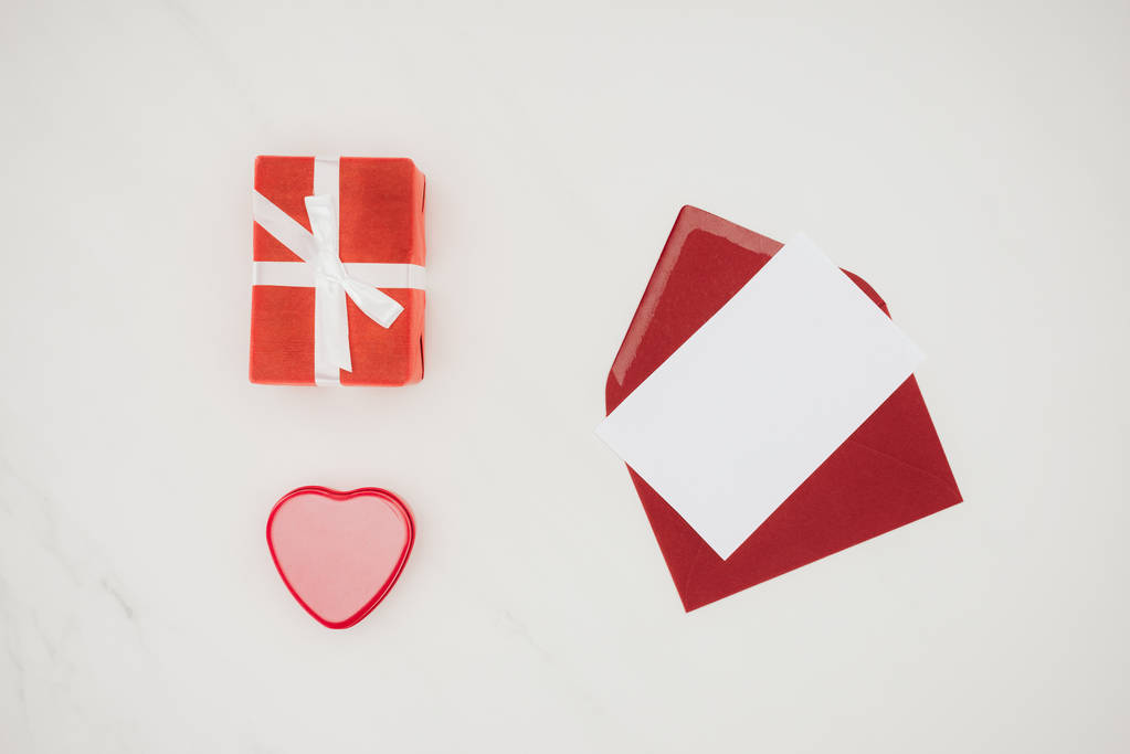 vista superior del sobre rojo abierto con papel en blanco y cajas de regalo aisladas en blanco
 - Foto, Imagen