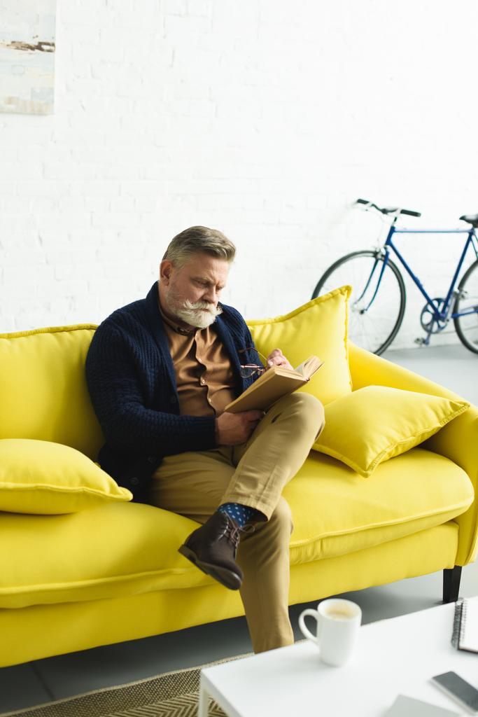 Sarı koltukta oturan ve kitap okuma komuta sizde sakallı  - Fotoğraf, Görsel