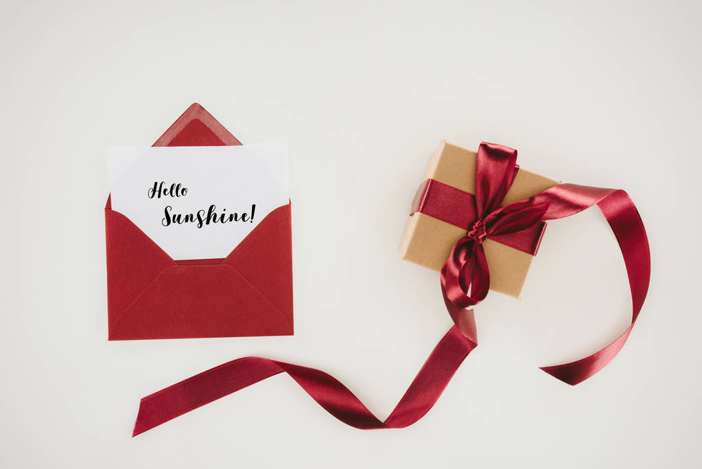 top view of red envelope with hello sunshine lettering on paper and gift box isolated on white - Photo, Image