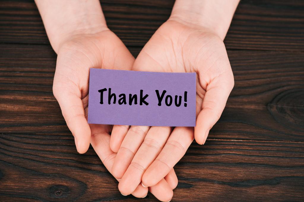 cropped shot of woman holding purple paper with thank you lettering over wooden table - Photo, Image