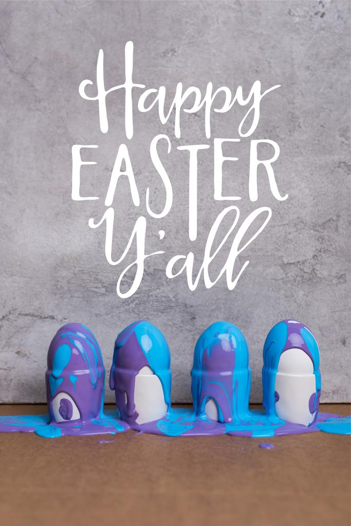 Pintura que cubre los huevos en tazas con letras felices de Pascua sobre fondo gris
 - Foto, imagen