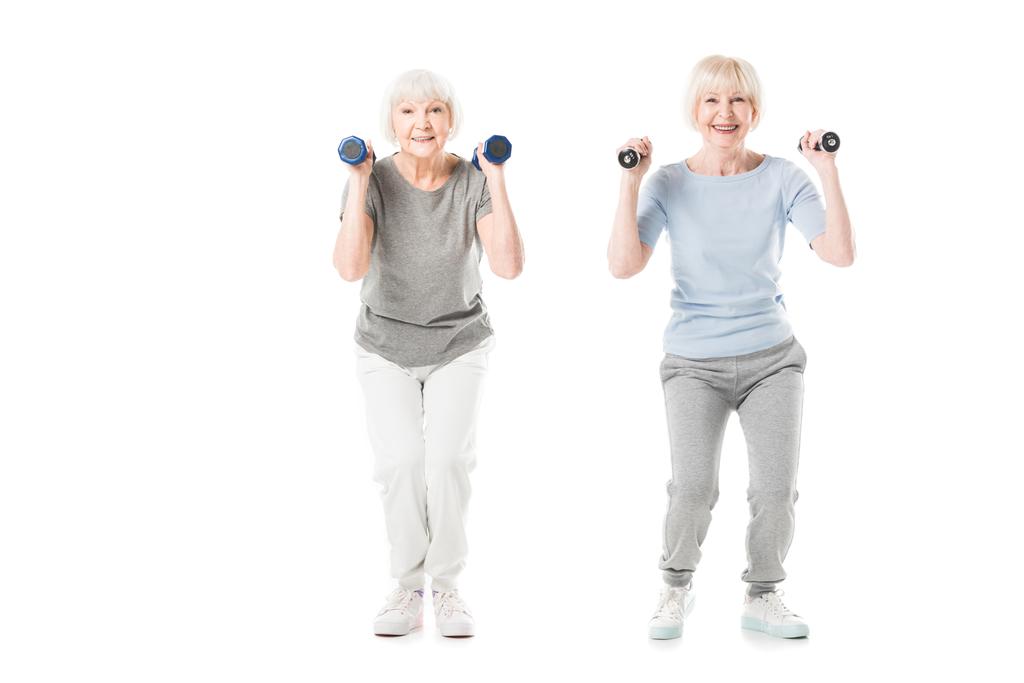 Усміхнені старші спортсмени роблять вправи з гантелями ізольовані на білому
 - Фото, зображення