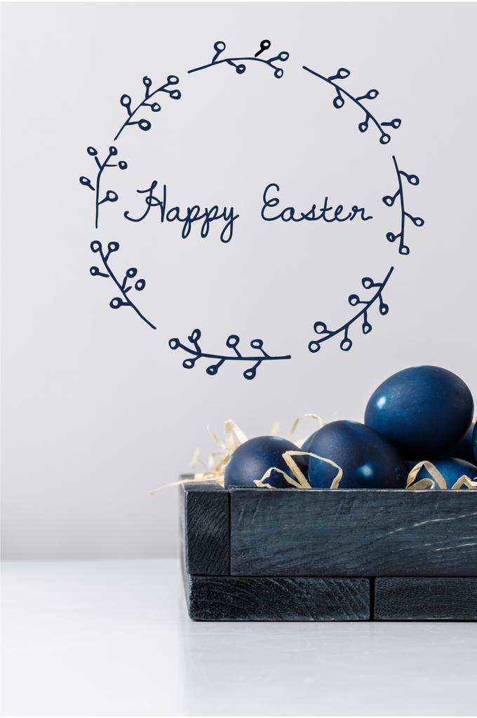 uova di Pasqua dipinte di blu in scatola con fieno decorativo e scritte pasquali felici
 - Foto, immagini