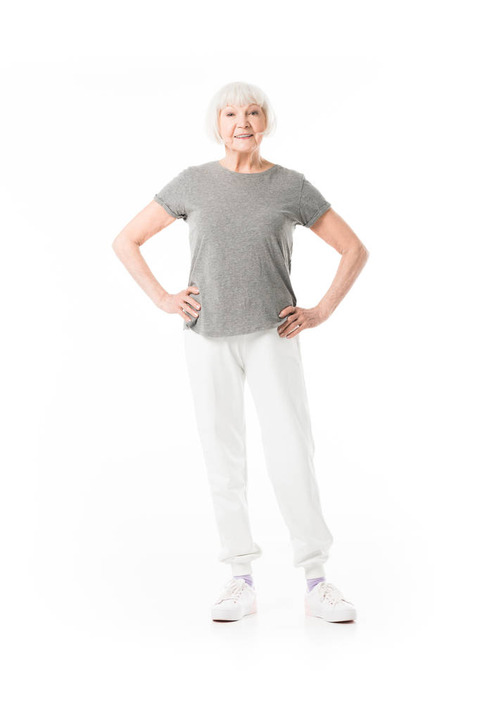 Senior Sportlerin steht mit den Händen auf der Taille isoliert auf weiß  - Foto, Bild