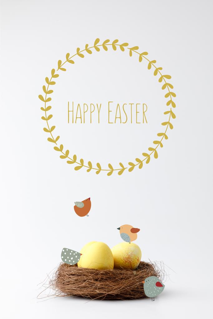 uova di Pasqua dipinte di giallo in nido decorativo con uccelli disegnati e felice iscrizione pasquale su bianco
 - Foto, immagini