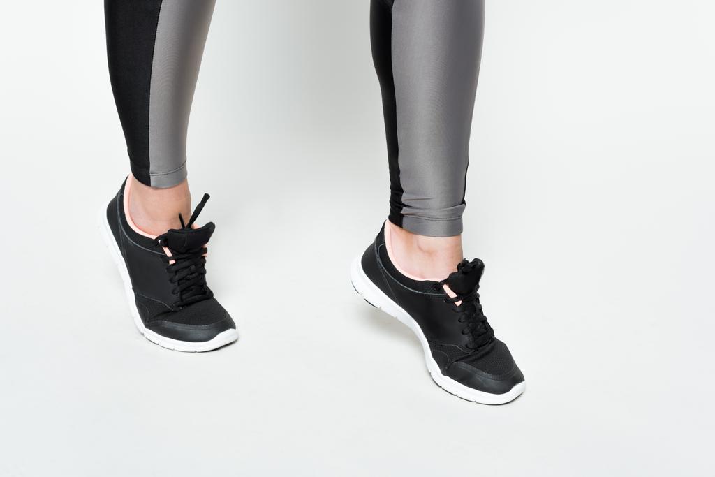 Close-up beeld van vrouwelijke benen in sport schoenen geïsoleerd op wit - Foto, afbeelding