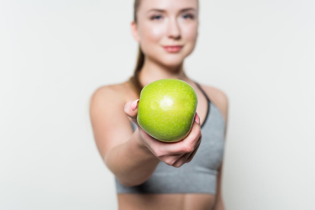 Apfel in der Hand von Fitness-Mädchen isoliert in weiß - Foto, Bild