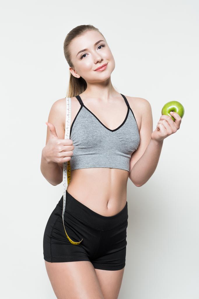 Lächelnde Fitness-Frau mit Apfel und Maßband auf weißem Grund - Foto, Bild