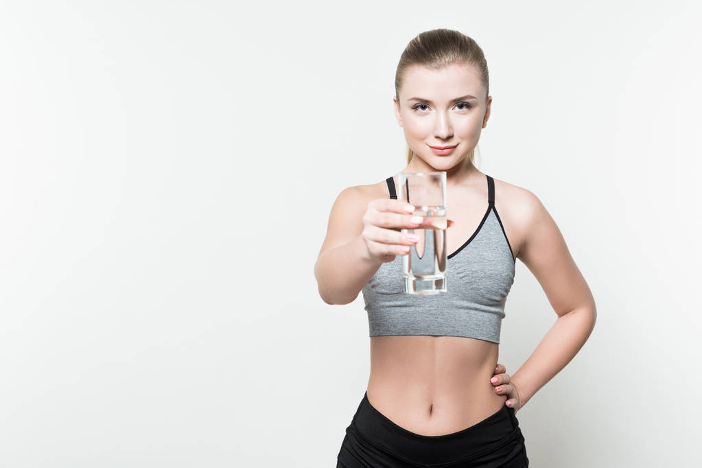 Giovane ragazza sportiva in possesso di un bicchiere d'acqua isolato su bianco
 - Foto, immagini