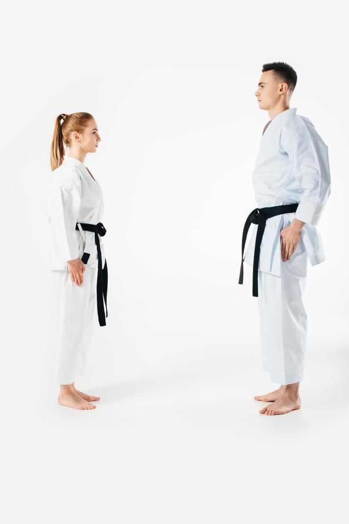 Karate strijders permanent en kijken elkaar geïsoleerd op wit - Foto, afbeelding