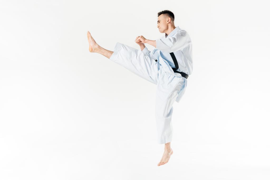 Seitenansicht des männlichen Karatekämpfertrainings isoliert auf weiß - Foto, Bild