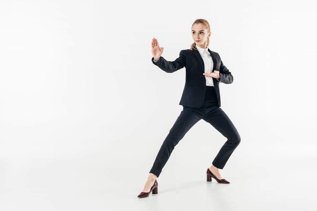 Geschäftsfrau im Anzug steht in Karate-Position und schaut isoliert auf weißem Grund weg - Foto, Bild
