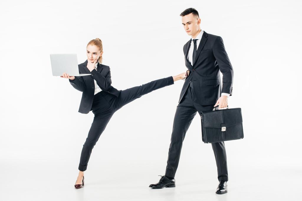 бизнесвумен держит ноутбук и пинает бизнесмена изолированы на белом
 - Фото, изображение