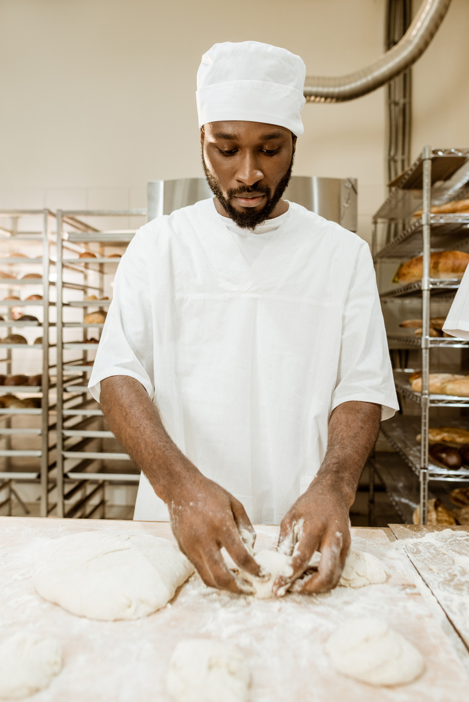 apuesto panadero afroamericano preparando masa cruda para pastelería en la fabricación de hornear
 - Foto, imagen