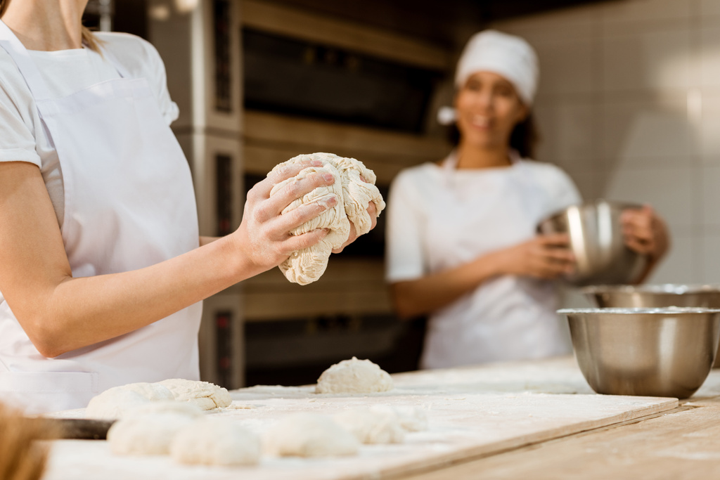 cropped shot of female baker kneading dough at baking manufacture - Photo, Image