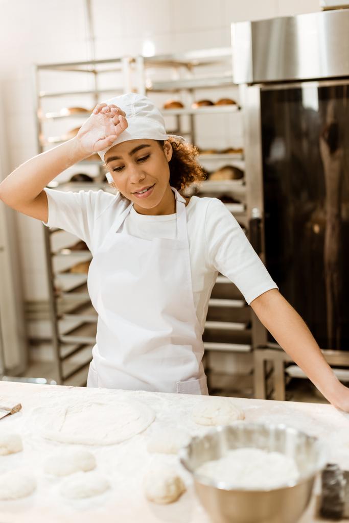 overworked female baker wiping sweat from forehead at baking manufacture - Photo, Image