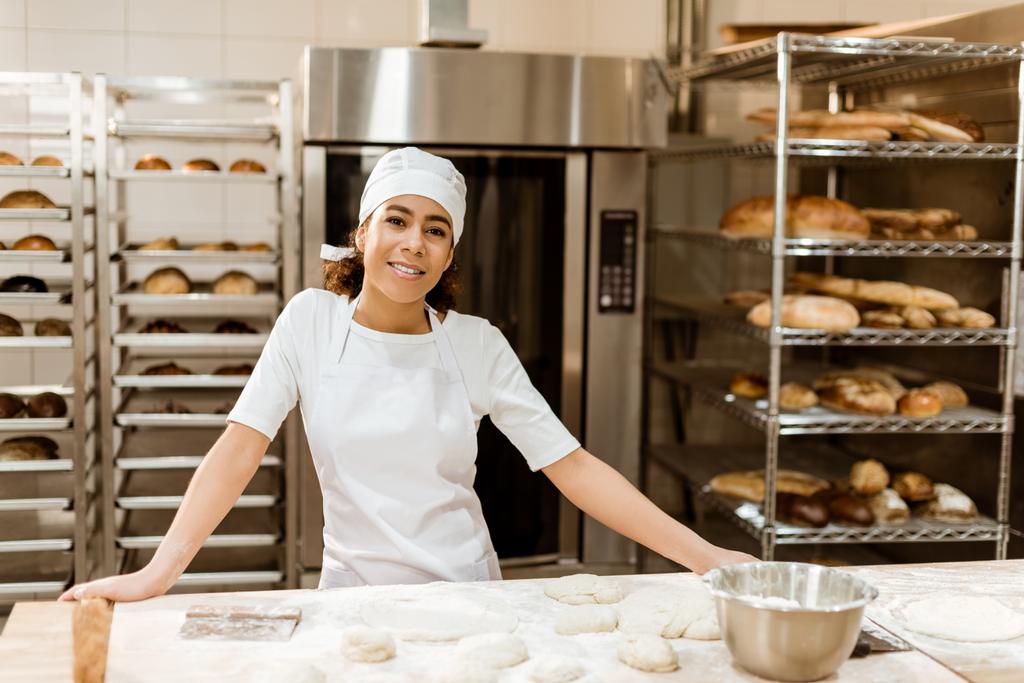 vrouwelijke baker permanent op werkplek op bakken vervaardiging - Foto, afbeelding