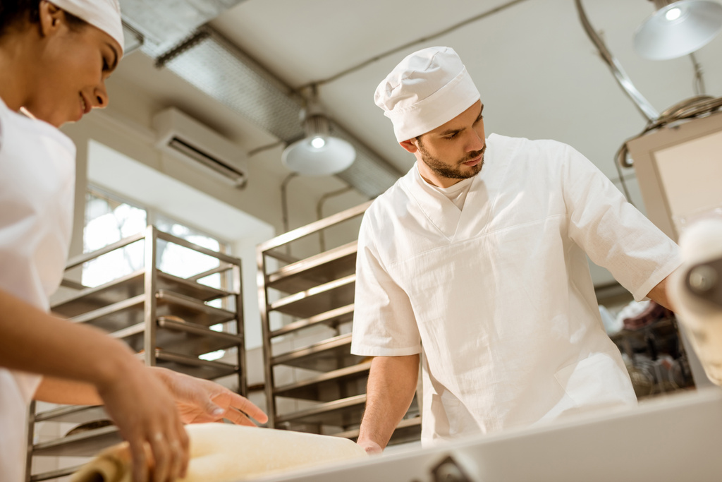 若い自信を持ってパン製造のベーキングで産業生地をローラーでの作業 - 写真・画像
