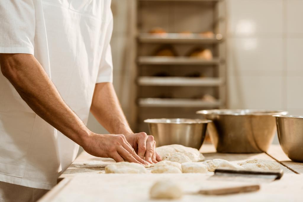 cropped shot of baker preparing raw dough on baking manufacture - Photo, Image