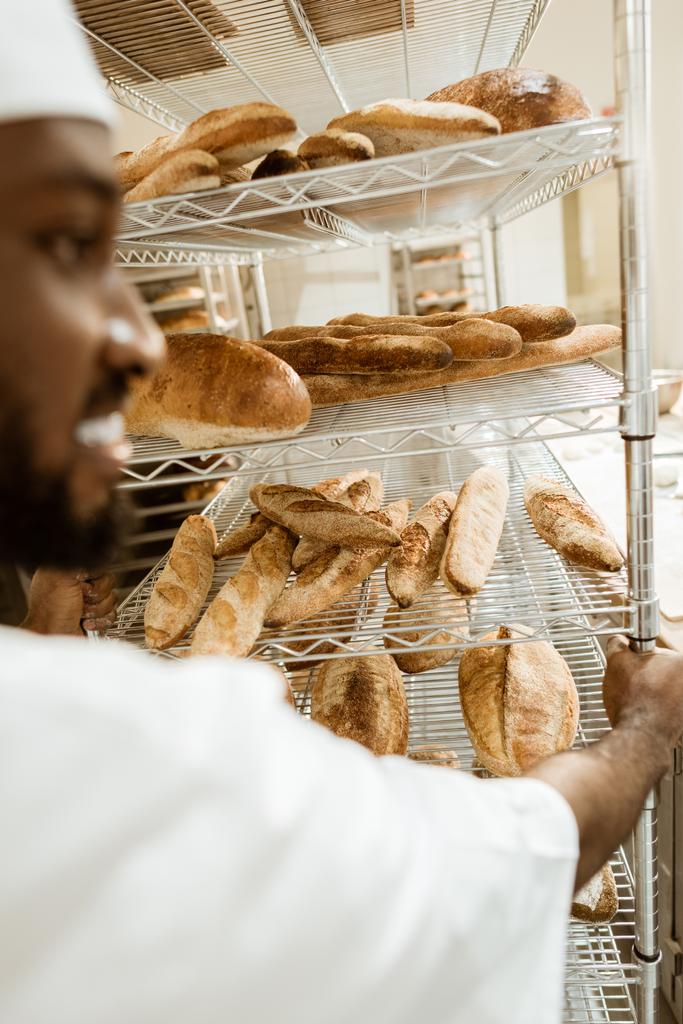 primo piano di panettiere afro-americano scaffali guida di pane fresco sulla fabbricazione di cottura
 - Foto, immagini