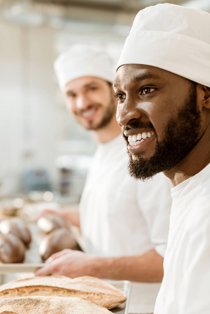 handsome young bakers in hats at baking manufacture - Photo, Image