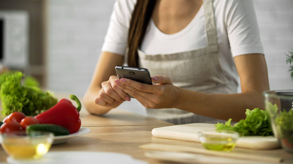 女性のキッチンでは、スマート フォンでのサラダのレシピを選択するアプリケーションを料理 - 写真・画像