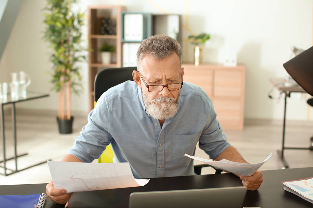 Senior man working with documents at table in office - Photo, Image