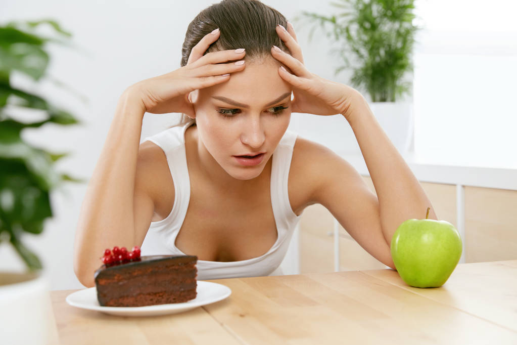 Dieta i odżywianie. Kobieta, wybór między ciasto i Apple. - Zdjęcie, obraz