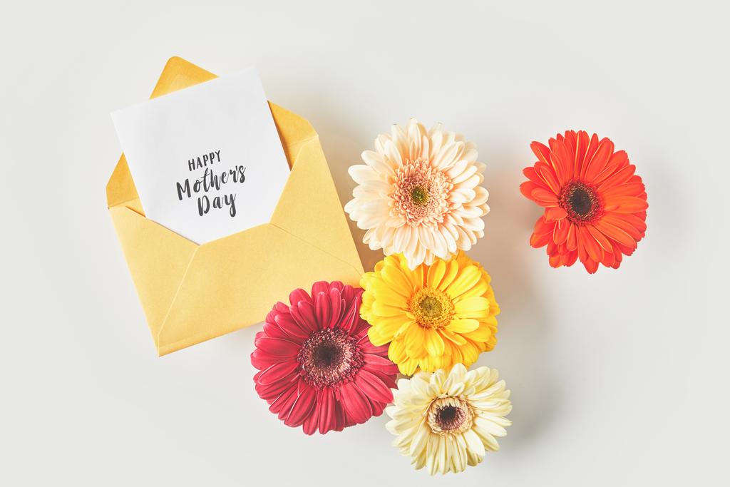top view of happy mothers day greeting card and beautiful gerbera flowers on grey - Photo, Image