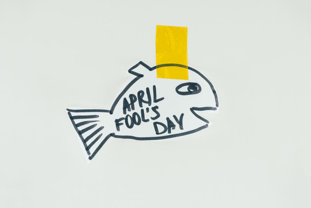 Nahaufnahme handgezeichneter Fische mit Aprilscherz-Schriftzug und Klebeband isoliert auf grau, Aprilscherz-Urlaubskonzept - Foto, Bild