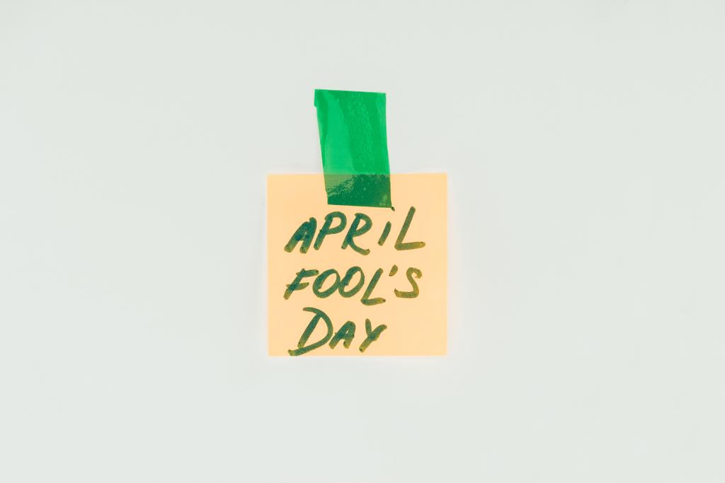 Zobacz Uwaga z kwietnia, dzień głupców napis i Przyklejony taśmą na białym tle na szary, kwietnia fools dzień koncepcji z bliska - Zdjęcie, obraz