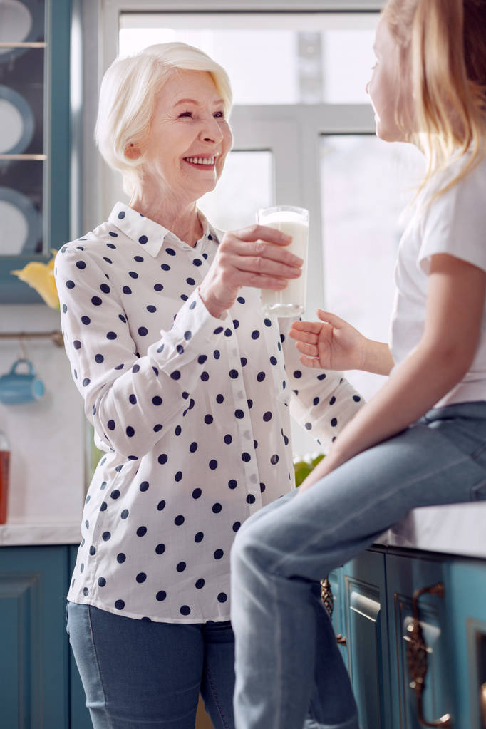 Przyjemna kobieta oferuje jej wnuczka do picia mleka - Zdjęcie, obraz