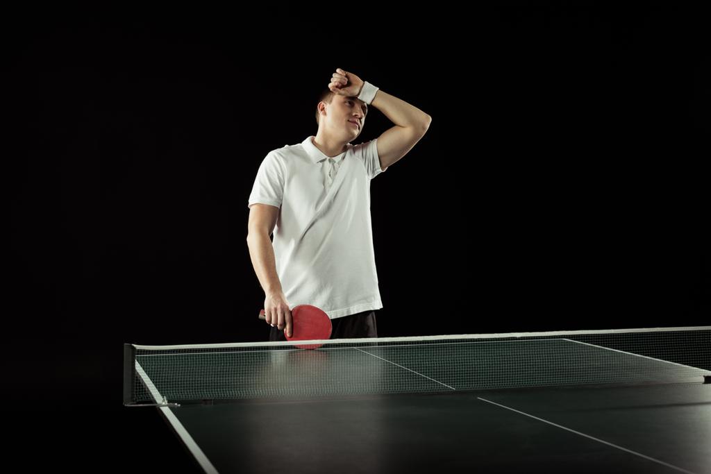 втомлений тенісист у формі біля тенісного столу ізольований на чорному
 - Фото, зображення