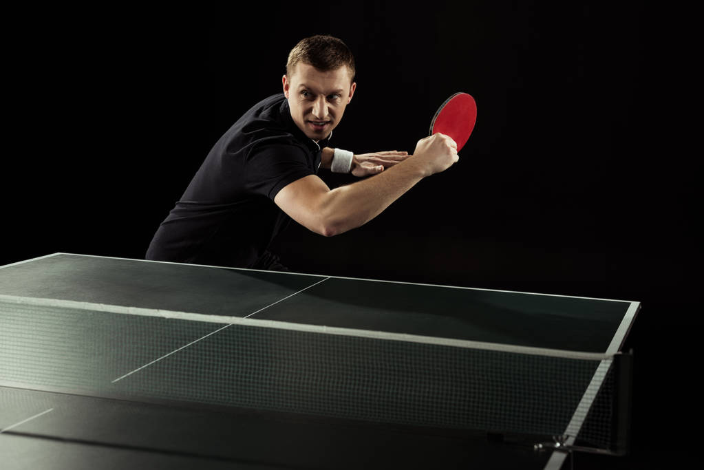 portrait of emotional tennis player playing table tennis isolated on black - Photo, Image