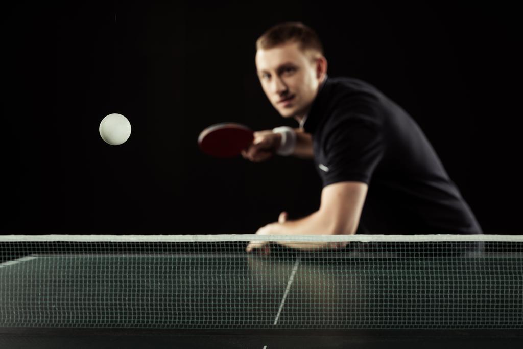 selective focus of young tennis player in uniform playing table tennis isolated on black - Photo, Image