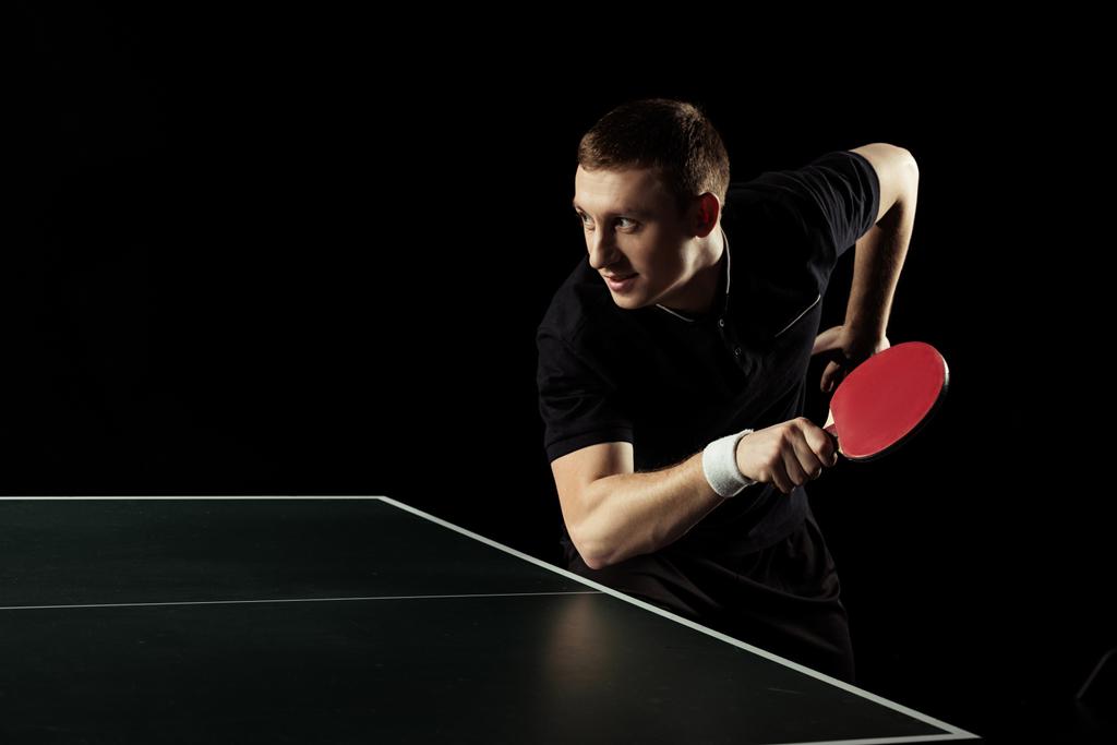 Widok z boku z młody tenisista praktykujących w tenisie stołowym na czarnym tle - Zdjęcie, obraz