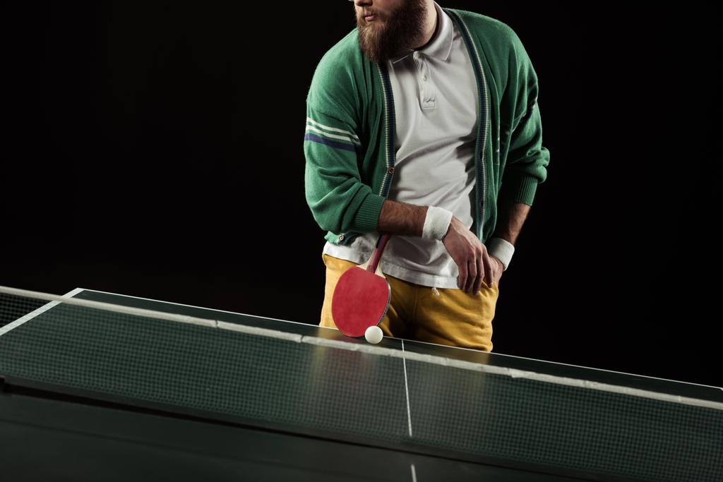 Teilansicht eines Tennisspielers mit Schläger, der isoliert auf schwarz an der Tischtennisplatte steht - Foto, Bild