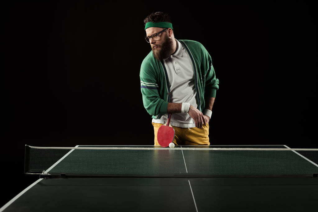 bearded tennis player leaning on racket on tennis table isolated on black - Photo, Image